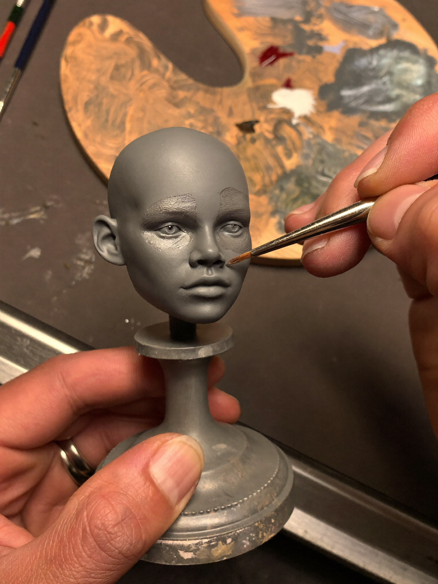 Artist hand-painting skin tones on a portrait sculpture
